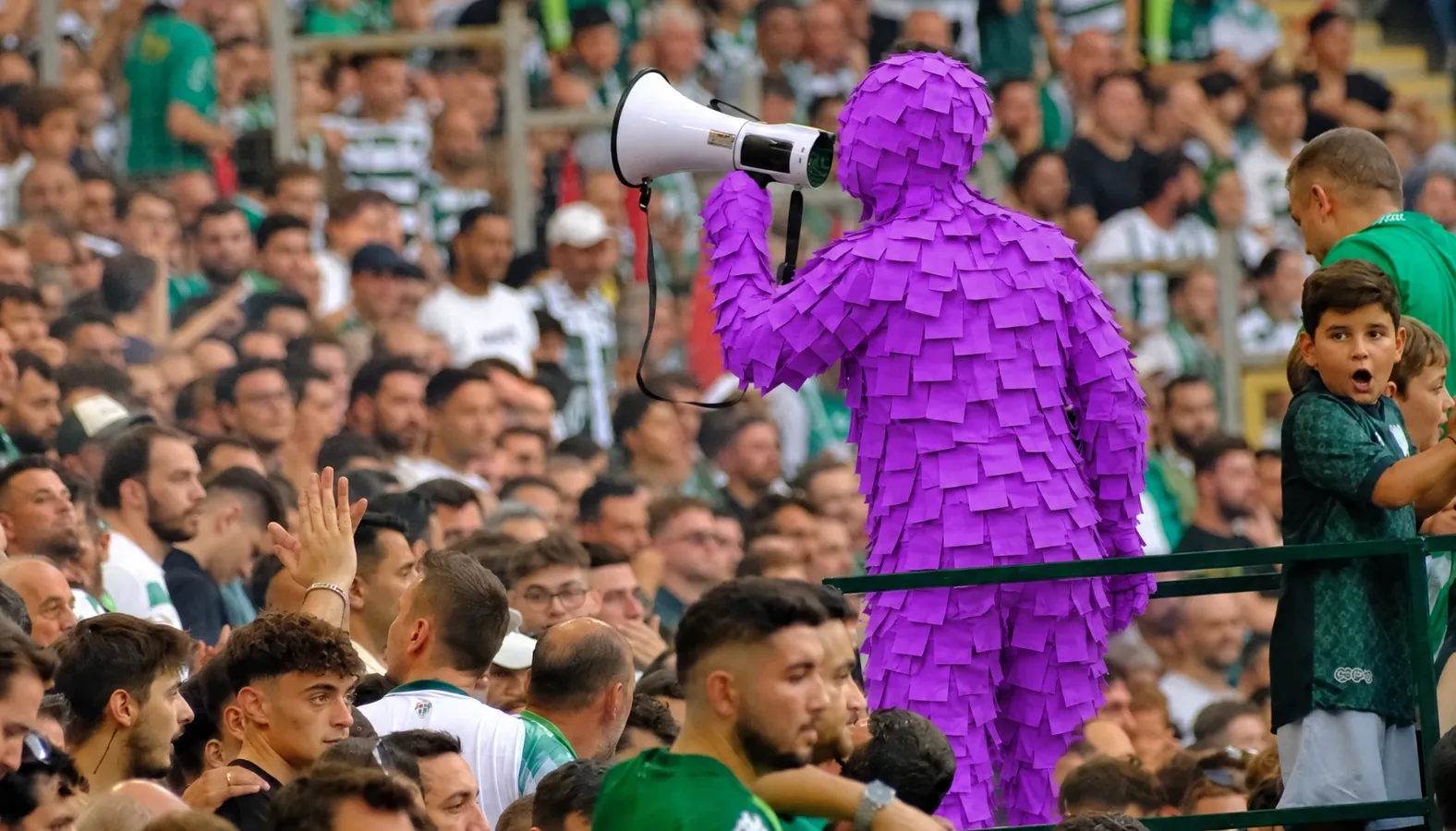 Purple Post-it man leading the crowd's chants through a megaphone